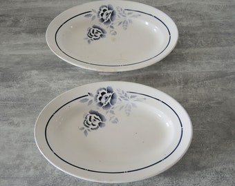 May include: Two white oval serving dishes with blue floral designs and a blue rim.