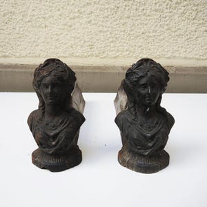 Peut inclure: Deux serre-livres anciens en fonte, chacun représentant un buste de femme avec des cheveux détaillés et des vêtements drapés. Les serre-livres sont gris foncé avec un aspect vieilli, suggérant l'âge. Ils sont conçus pour tenir debout.