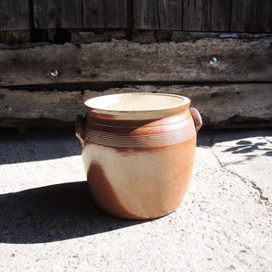 May include: A white ceramic mug with a black handle and the text "But First, Coffee" in a black, handwritten-style font. The mug is on a white surface.