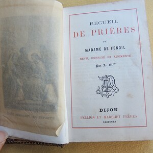 Puede incluir: Un libro antiguo titulado "Recueil de Prières de Madame de Fenoil" con una ilustración en blanco y negro en la portada. El libro está encuadernado en rojo y dorado y tiene un diseño decorativo en el lomo.