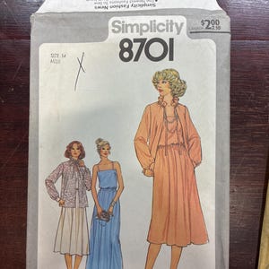 May include: A Simplicity 8701 sewing pattern envelope for size 14. The front features illustrations of three outfits: a patterned blouse with a skirt, a blue sleeveless floor-length dress, and a peach-colored dress with a matching jacket.