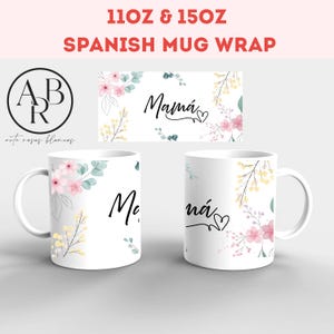 Op de afbeelding: Twee witte keramische mokken met bloemenmotieven en het woord "Mamá" in zwarte letters. De mokken zijn 11 oz en 15 oz.