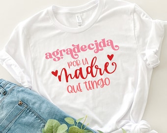 May include: White t-shirt with pink and red lettering that says "agradecida por la madre que tengo" with two red hearts.