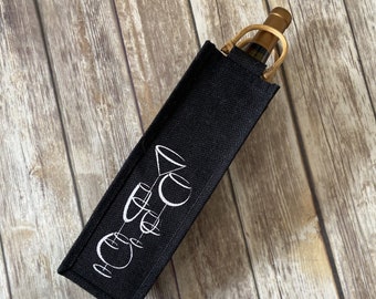 May include: Black fabric wine bottle carrier with a white design of wine glasses. The carrier has a gold metal zipper.