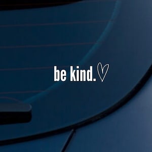 May include: White vinyl sticker with the text "be kind." and a small heart symbol on a dark blue car.