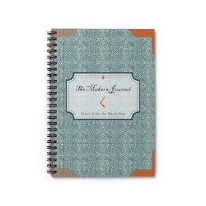 May include: A spiral-bound notebook with a teal cover featuring a white geometric pattern. A central label reads The Maker's Journal and Notes from the Workshop in black text, accented by orange geometric shapes and brown corner details.