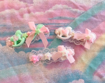 Könnte beinhalten: Drei rosa und weiße Haarklammern mit Spitzenbesatz und Miniaturspielzeugfiguren. Die Figuren sind ein Schaukelpferd, ein Schaukelpferd mit einem Herzen und ein Schaukelpferd mit einem Stern.