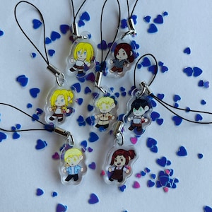 Op de afbeelding: Set van acht kleurrijke anime-personagecharms met een zwarte koord eraan bevestigd. De charms zijn gemaakt van helder acryl en tonen verschillende personages met verschillende gezichtsuitdrukkingen.