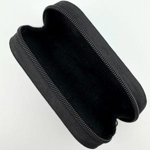 May include: Black zippered case with a soft black interior lining. The case is made of a durable fabric and has a zipper closure.