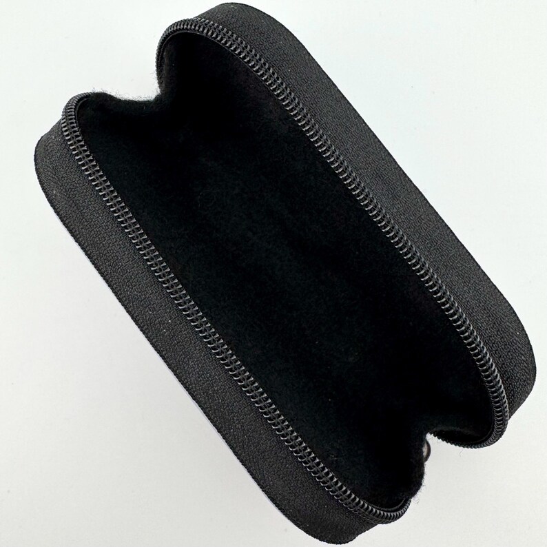 May include: Black zippered case with a soft black interior lining. The case is made of a durable fabric and has a zipper closure.