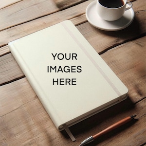 May include: A white notebook with a black elastic band and the text "YOUR IMAGES HERE" on the cover. The notebook is lying on a wooden surface with a pen and a cup of coffee.