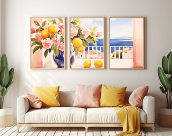 May include: A triptych of framed wall art prints featuring watercolor illustrations of yellow lemons, pink flowers in blue vases, and a coastal balcony view overlooking a blue sea and white buildings under a bright sky.