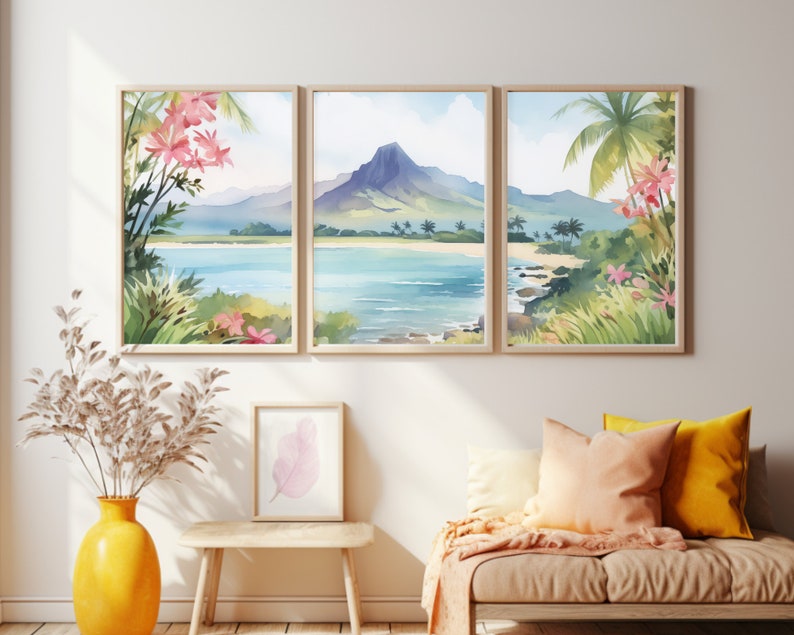 May include: A triptych of watercolour landscape prints in light wood frames depicting a tropical beach with a central mountain, palm trees, and pink flowers. The artwork is displayed above a wooden bench with a yellow vase and a small framed leaf print.
