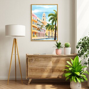 Peut inclure: Une peinture encadr&eacute;e d'une ville color&eacute;e avec un clocher d'&eacute;glise et des palmiers. Les b&acirc;timents sont peints dans des tons de jaune, rose et bleu. Les palmiers sont verts et le ciel est bleu.