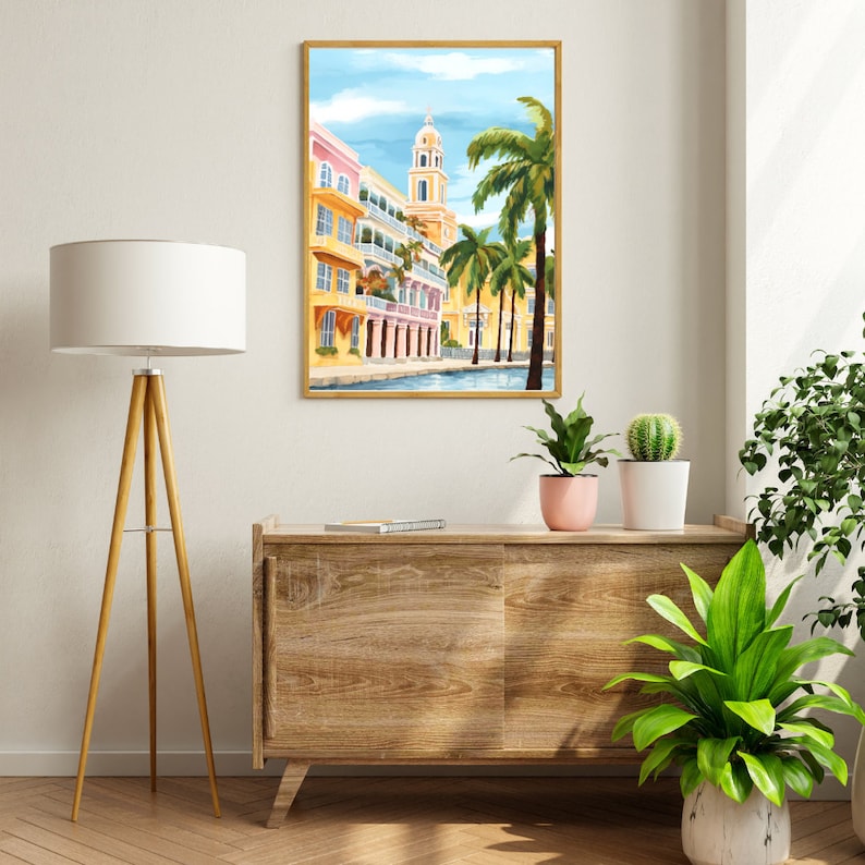 Peut inclure: Une peinture encadr&eacute;e d'une ville color&eacute;e avec un clocher d'&eacute;glise et des palmiers. Les b&acirc;timents sont peints dans des tons de jaune, rose et bleu. Les palmiers sont verts et le ciel est bleu.