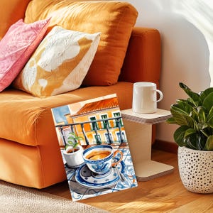 May include: A watercolor painting of a cup of coffee on a balcony overlooking a building with a red tile roof. The cup is blue and white with a floral design. The balcony is tiled in blue and white.
