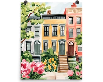 May include: A vertical art print depicting a row of three townhouses in white, yellow, and coral. The buildings feature dark rectangular windows, arched doorways, and front steps. Lush green trees and vibrant pink and yellow flowers fill the foreground.