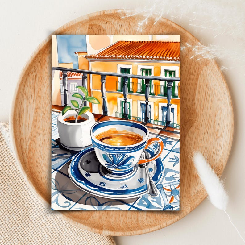 May include: A watercolor painting of a cup of coffee on a blue and white patterned saucer with a spoon. The cup is sitting on a tiled balcony overlooking a yellow building with green shutters.