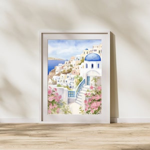 Puede incluir: Una l&aacute;mina de acuarela enmarcada que representa un pueblo costero mediterr&aacute;neo con edificios blancos, c&uacute;pulas azules y escaleras de piedra. La escena muestra flores de buganvilla de color rosa intenso en primer plano y el mar azul.