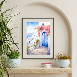 May include: A framed wall art print depicting a Mediterranean coastal scene with white buildings, a bright blue arched door, and vibrant pink bougainvillea flowers. The artwork features a stone pathway leading toward a sea view under a clear blue sky.