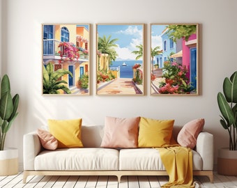 May include: A set of three framed wall art prints depicting Mediterranean coastal scenes with colorful buildings, vibrant pink flowers, lush green palm trees, and a blue sea with a sailboat under a bright sky, displayed above a white sofa.