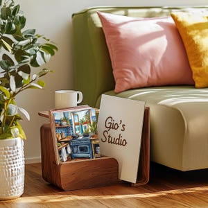 May include: A wooden magazine rack with a white card that says "Gio's Studio" and a stack of colorful postcards featuring a kitchen scene.
