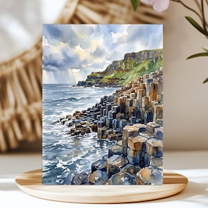 May include: A watercolor painting depicting a coastal landscape with hexagonal basalt columns extending into the sea. The scene features dark, stormy clouds above a green cliffside, with blue ocean waves washing over the dark, geometric rock formations.