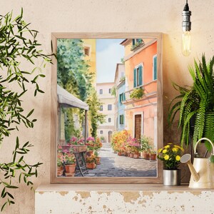 May include: Watercolor painting of a narrow street in a European city. The street is lined with colorful buildings and potted plants. A white awning covers a cafe on the left side of the street.
