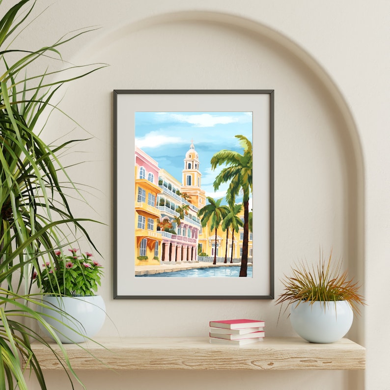 Peut inclure: Une impression encadr&eacute;e d'une ville color&eacute;e avec un immeuble haut et des palmiers. Les b&acirc;timents sont peints dans des tons de jaune, rose et bleu. Les palmiers sont verts et ont une ambiance tropicale.