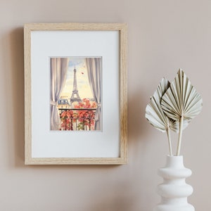 May include: A framed watercolor print featuring a view from a balcony looking toward the Eiffel Tower in Paris. The scene includes white curtains, a black wrought iron railing, and pink flowers, all encased in a light-colored wooden frame.