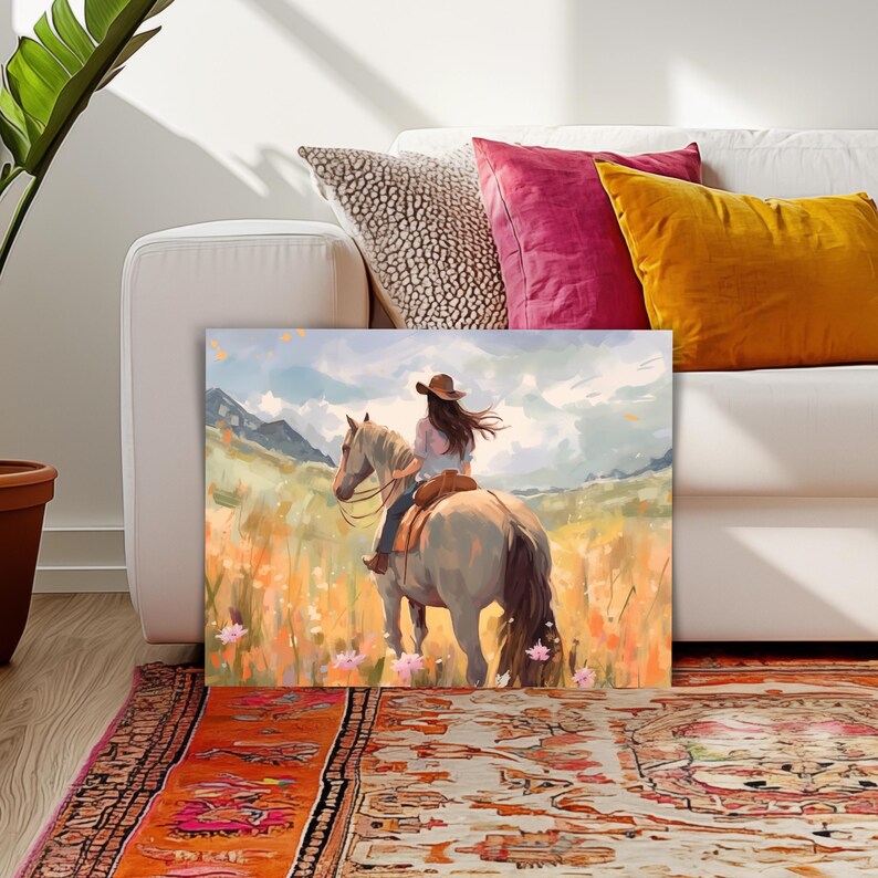 May include: A canvas print showing a person on horseback in a field of flowers. The rider, wearing a brown hat, is viewed from behind. The artwork uses a gentle colour palette, with mountains in the background and a bright sky.