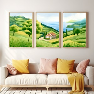 May include: Three framed landscape paintings in a green and blue colour scheme. The centre painting features a small white house with a red roof on a green hillside overlooking a blue body of water. The other two paintings feature green hillsides with trees.