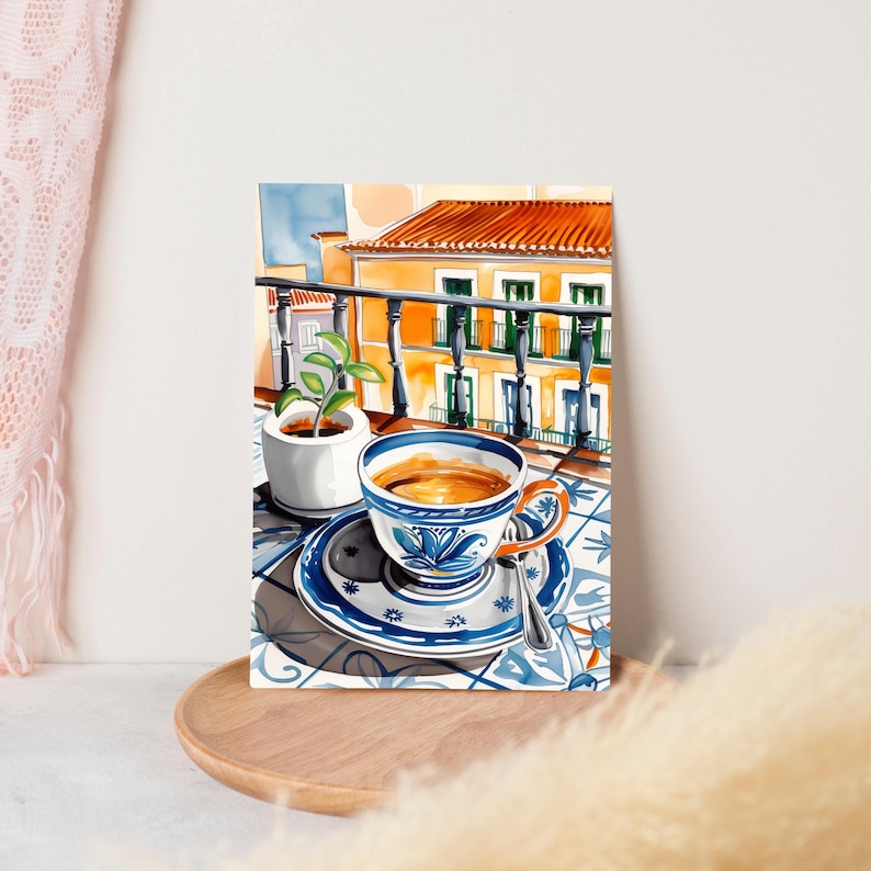 May include: A watercolor painting of a cup of coffee on a balcony overlooking a building with a tiled floor. The cup is blue and white with a floral design and is filled with coffee. The building is yellow with orange tile roof and has a balcony with a black railing.