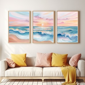 May include: Three framed prints of a beach scene with blue waves crashing on the shore and a pink and orange sunset in the background.
