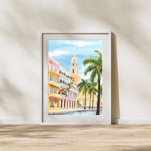 Peut inclure: Une peinture &agrave; l'aquarelle d'une ville color&eacute;e avec une haute tour blanche et des palmiers. Les b&acirc;timents sont peints dans des tons de jaune, rose et bleu, et les palmiers sont verts. La peinture est encadr&eacute;e dans un cadre blanc.