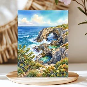 May include: A watercolor painting depicting a coastal landscape with a natural stone arch over turquoise ocean water. The scene features rugged cliffs, tide pools, and green coastal vegetation under a bright blue sky with soft white clouds.