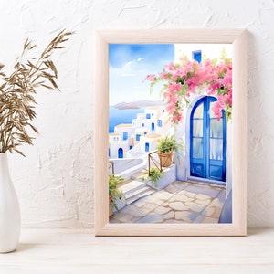May include: A framed watercolor print depicting a Mediterranean coastal scene with white buildings, blue doors, and pink bougainvillea flowers. The artwork features a stone pathway leading toward the sea under a bright blue sky, all encased in a light wood frame.