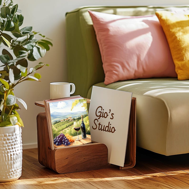 Puede incluir: Un revistero de madera con una tarjeta blanca que dice "Gio's Studio" y una pintura colorida de un vi&ntilde;edo con una copa de vino y una botella de vino.