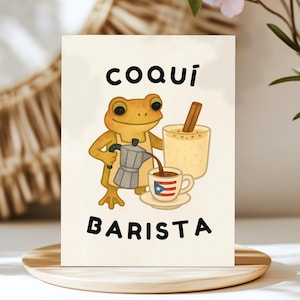 May include: A greeting card featuring a cartoon frog barista. The frog, wearing an apron, pours coffee from a silver pot into a cup with a Puerto Rican flag design. The card includes the words "COQUÍ BARISTA" in black letters, with a drink and cinnamon stick.