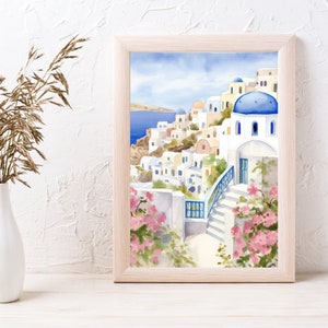 Puede incluir: Una pintura en acuarela enmarcada que representa un pueblo costero griego con edificios blancos, techos de c&uacute;pula azules y escaleras de piedra. La escena presenta flores de buganvilla de color rosa vibrante y un mar azul profundo.