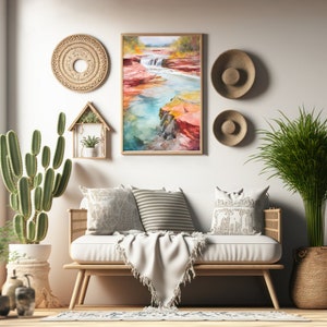 Puede incluir: Una pintura de acuarela de un r&iacute;o que fluye a trav&eacute;s de un ca&ntilde;&oacute;n con formaciones rocosas rojas y naranjas. La pintura est&aacute; enmarcada y colgada en una pared blanca sobre un sof&aacute; con almohadas y una manta.
