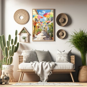 May include: A white sofa with a white throw blanket and cushions in a living room setting. The wall behind the sofa has a framed print of a colourful street scene with umbrellas.
