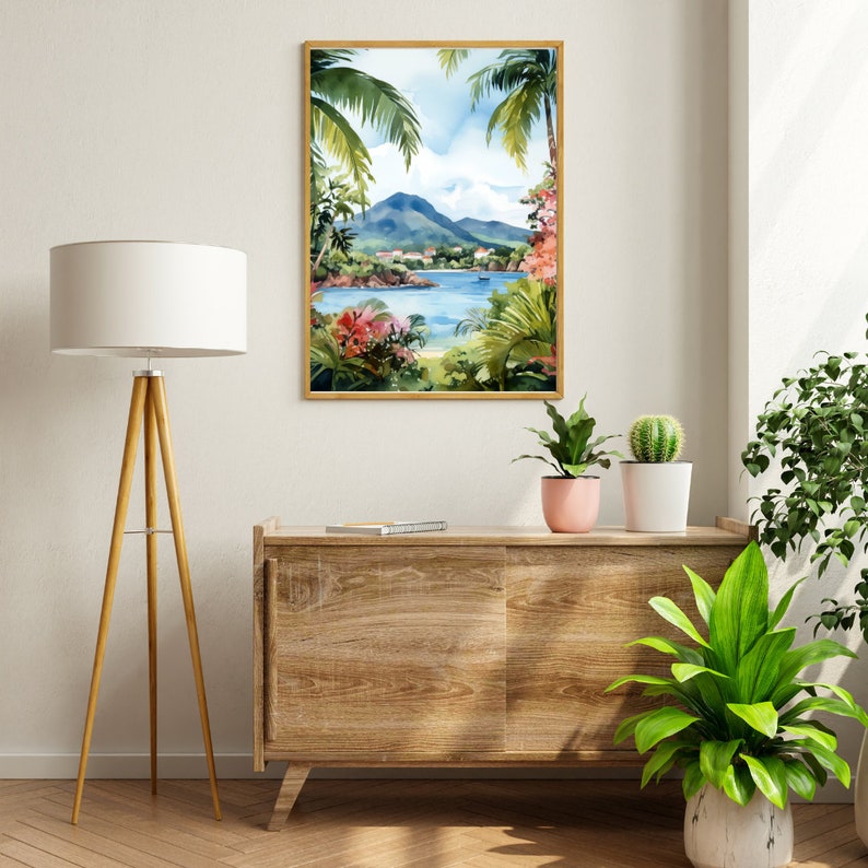 May include: A watercolor painting of a tropical island scene with lush green palm trees, a blue bay, and a mountain in the background. The painting is framed in a light wood frame and is hanging on a white wall.