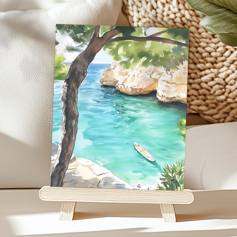 May include: Watercolor painting of a serene coastal scene. Turquoise water, rocky cliffs, and a small boat are visible. A tree frames the view, with green foliage and a clear blue sky. The artwork is displayed on a small wooden easel.