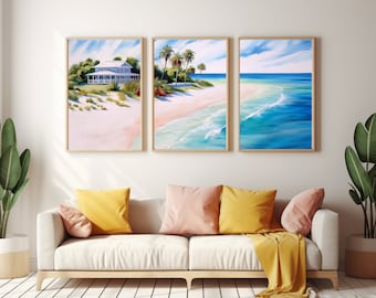 May include: Three framed paintings depicting a beach scene. The leftmost painting shows a white house with a green roof on a sandy beach. The middle painting shows palm trees on a sandy beach with blue water. The rightmost painting shows a blue ocean with white waves.