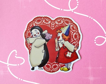 May include: A sticker featuring two cartoon clowns on a red heart-shaped doily. One clown, in a white and black outfit, offers flowers to the other clown, who wears a red dress and party hat. The background is pink with white decorative lines.