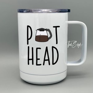May include: White ceramic travel mug with a black and white illustration of a coffee pot and the text "Pot Head".