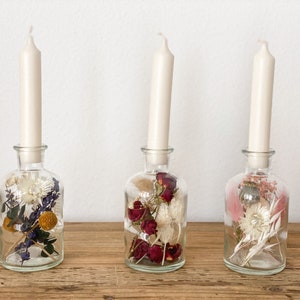Droogbloemen in een glas als kaarsenhouder. Droogbloemenboeket in een glas in verschillende kleuren