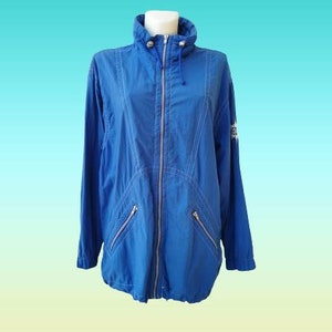 Puede incluir: Una chaqueta azul con capucha, cierre de cremallera y dos bolsillos en la parte delantera. La chaqueta tiene un logotipo blanco en la manga derecha.