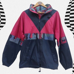May include: A blue, pink, and camouflage patterned jacket with a zipper closure. The jacket has a hood and a drawstring at the bottom.